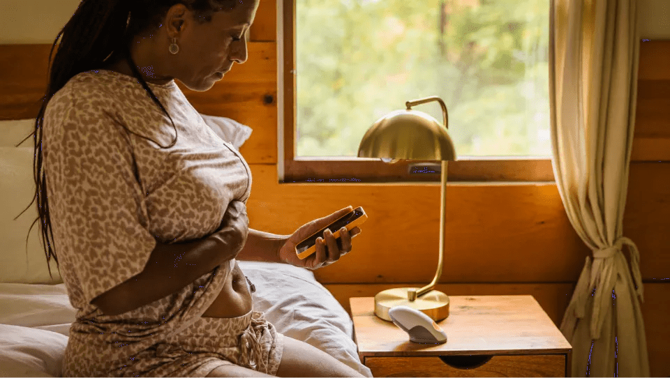 Woman viewing her personal health app on her phone in her bedroom.