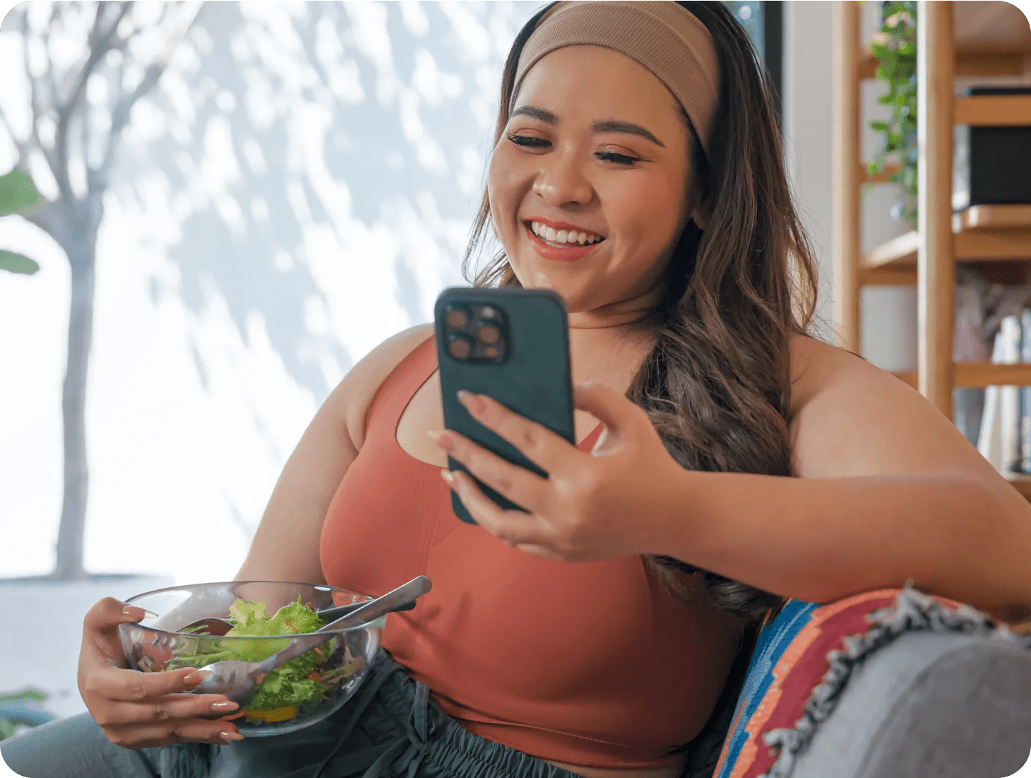 Woman eating a healthy salad, and interacting with her virtual care program for obesity.
