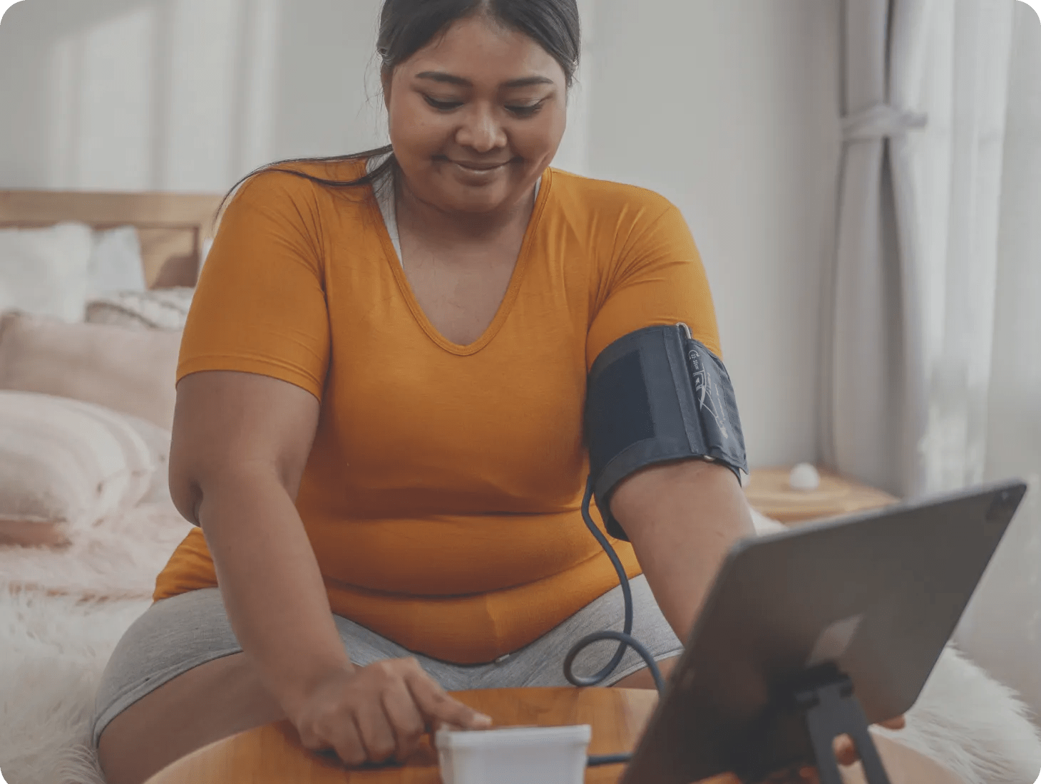 A woman checking her blood pressure with a connected cuff device as part of her virtual, chronic care program — Verily Lightpath.