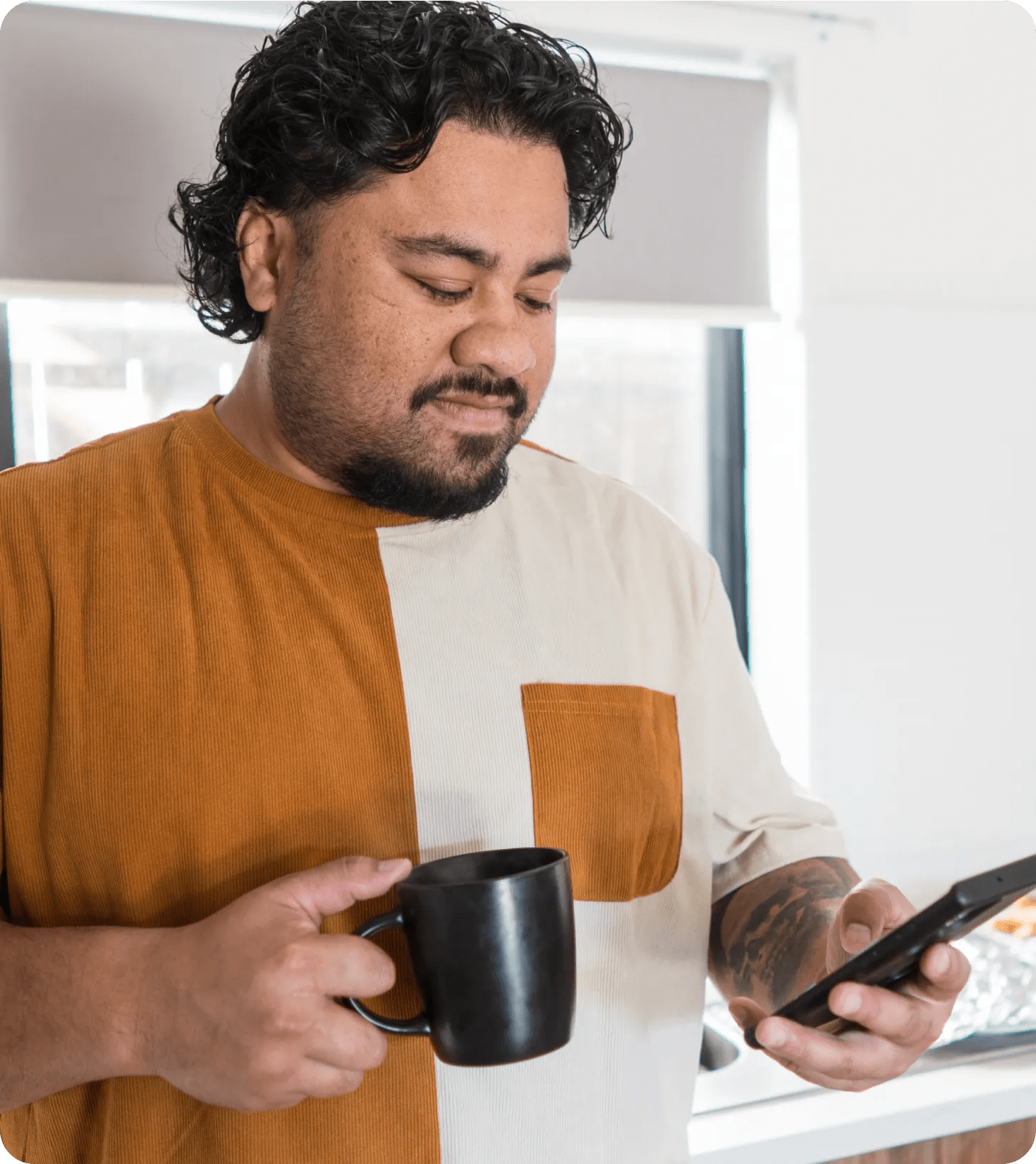 A Samoan man in his forties with prediabetes and hypertension looking at his virtual chronic care program app for healthy breakfast choices while having coffee in his kitchen.