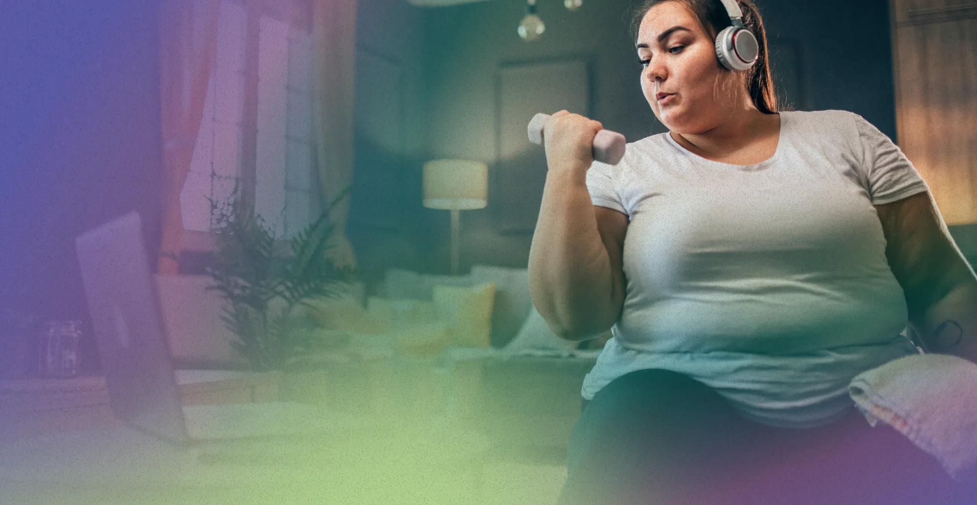 An obese woman in her early thirties doing bicep curls at home with water nearby. She’s sticking to the convenient activity plan she created with her virtual program care team.