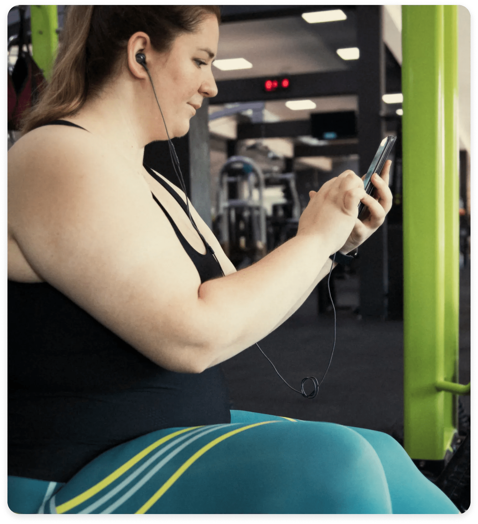 Woman in her late twenties, working out while engaging the Verily Me app within her smart phone