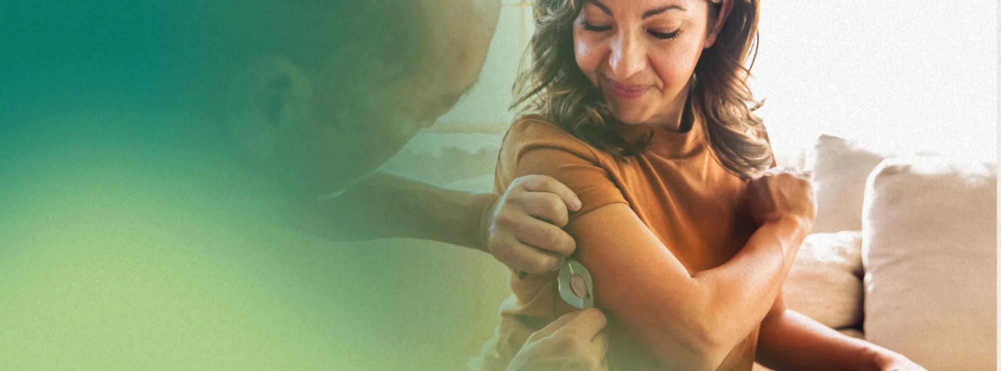A hispanic-descent woman with diabetes getting fitted with a CGM. She received the connected device for better diabetes management as part of her virtual care program.