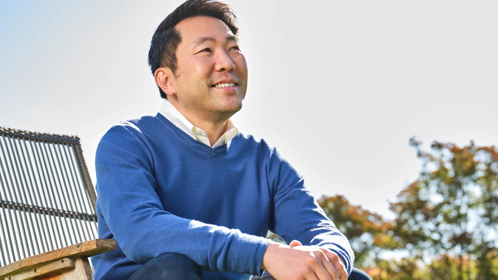 Photograph of Verily CPO, Myoung Cha, sitting outdoors in a wooden chair, looking off to the side.