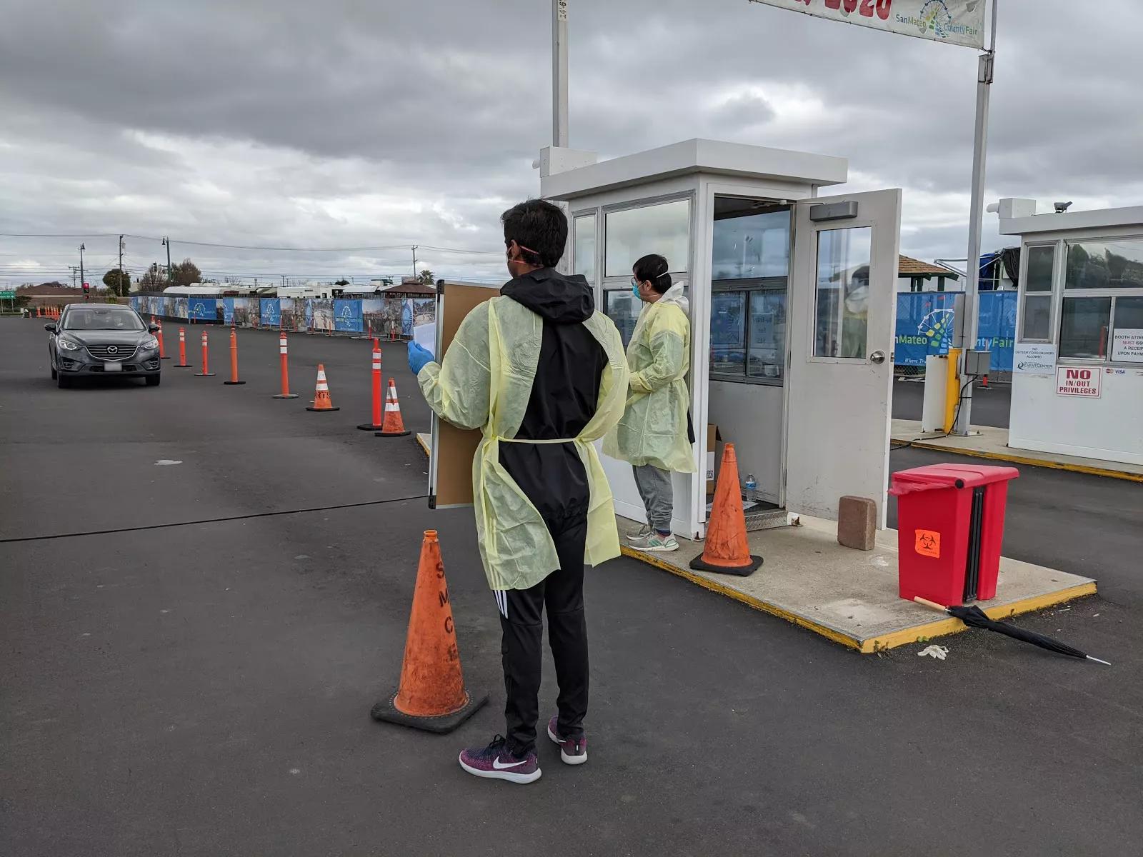 Site personnel in personal protective equipment (PPE) direct individuals to mobile testing site.